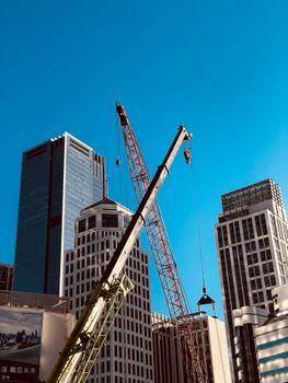 Skyscrapers under construction against a vivid blue sky, highlighting urban development.