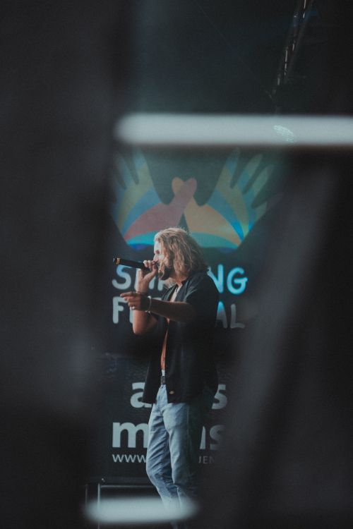 Free Adult man singing at an outdoor music festival with a microphone. Stock Photo