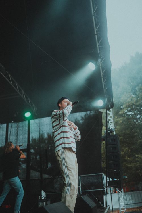 Free Energetic singer performing at an outdoor concert under dynamic stage lights. Stock Photo
