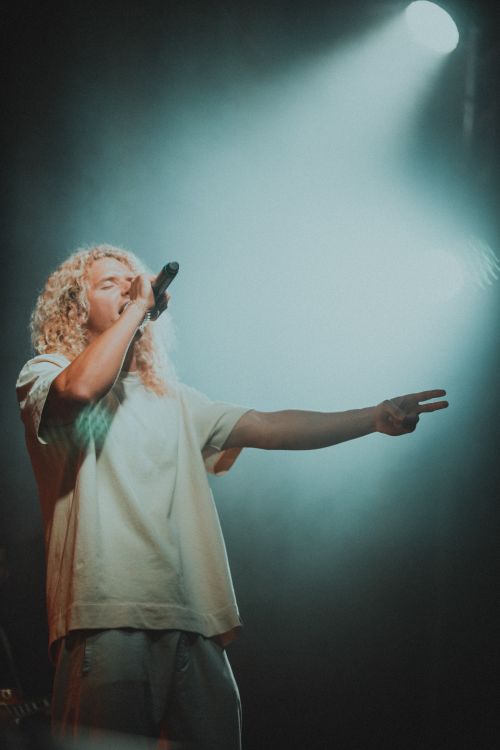 Free A dynamic photo of a singer performing on stage with a microphone under dramatic lighting. Stock Photo