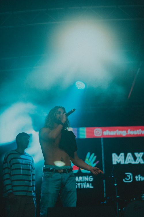 Free Dynamic performance at a music festival with shirtless male singer under vibrant stage lights. Stock Photo