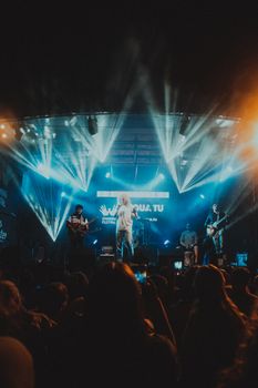 A dynamic rock band performs on stage with dramatic lighting at a night concert, captivating the audience.