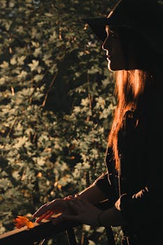 一个女人的剪影被温暖的秋光和秋天的树叶包围着