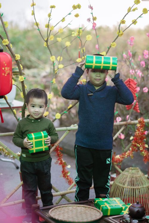 Free Two children holding festive gift boxes outdoors with colorful decorations. Stock Photo