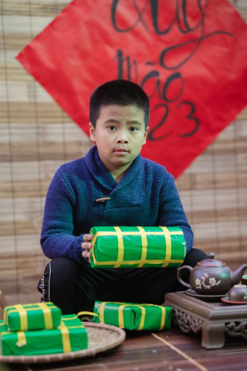 Free Young boy holding gifts, celebrating Lunar New Year indoors with vibrant decorations. Stock Photo