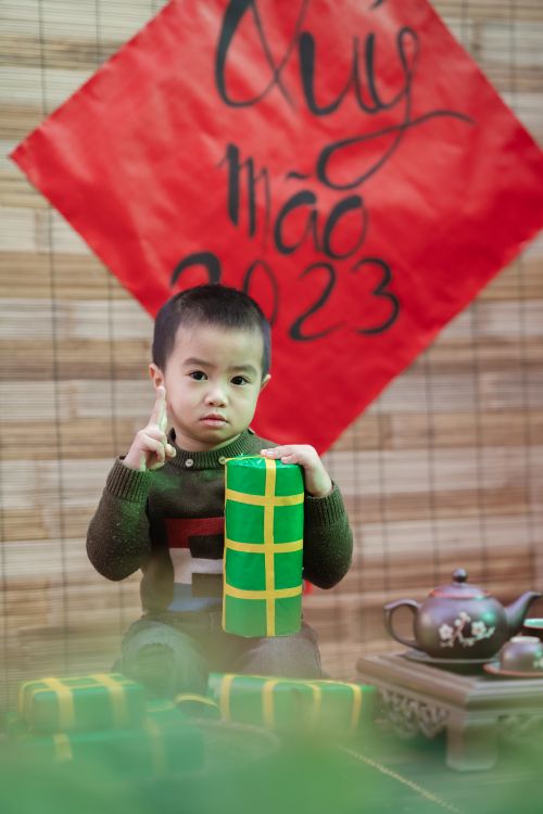 Free Child holding a gift in a festive Vietnamese setting with a subtle New Year theme. Stock Photo