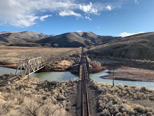 Free Aerial view of a railway bridge spanning the Humboldt River with surrounding mountains in Nevada. Stock Photo