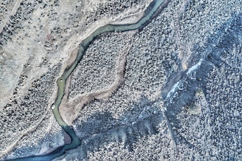 Aerial View of a Frozen River Between Snow Covered Ground