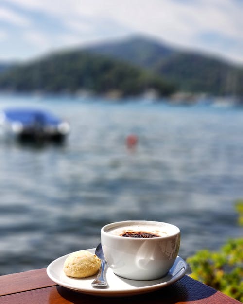 Photo En Gros Plan D'une Tasse De Thé En Céramique Blanche Sur Une Soucoupe à Côté Du Plan D'eau