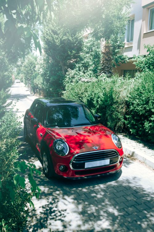 Free A vibrant red car parked in a leafy, sunlit alley in İzmir, Turkey. Stock Photo