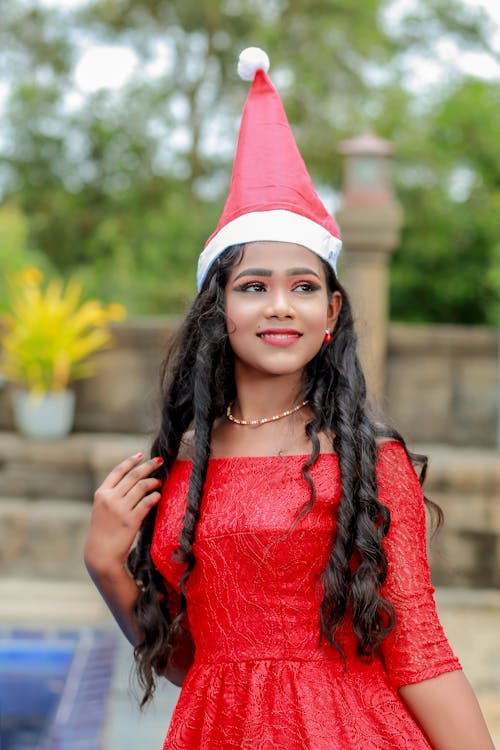 Young Woman Posing in Red Santa Hat and Red Off Shoulder Dress