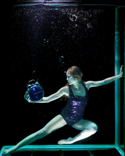 水下举行圆形蓝色模拟铃闹钟的女人