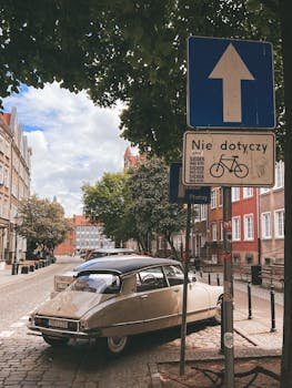 Classic Citroen DS parked in an urban Gdańsk street with road signs and European architecture.