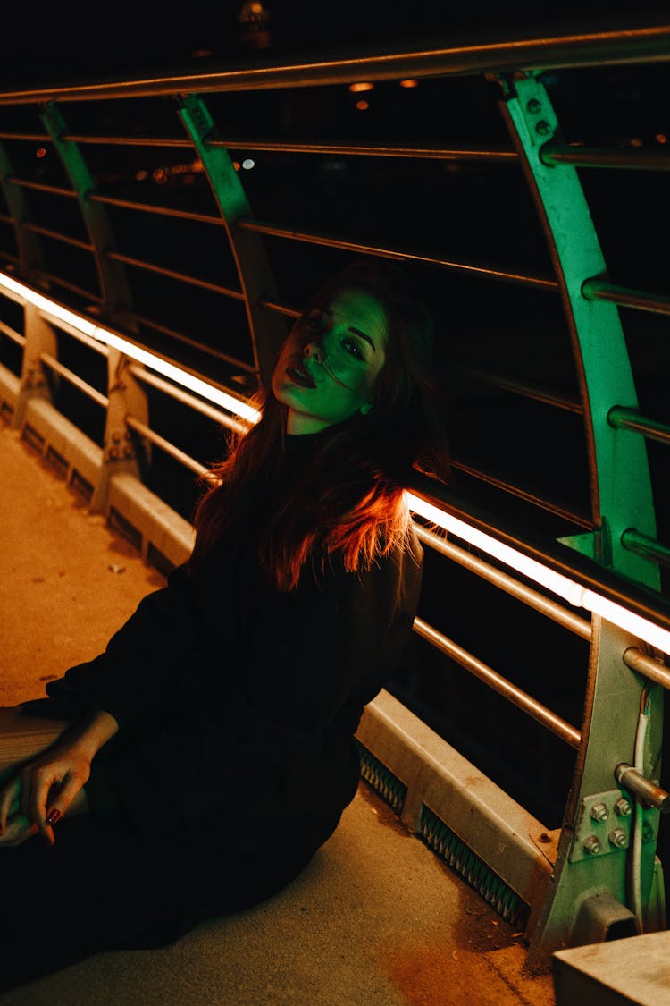 Woman Sitting At Bridge At Night