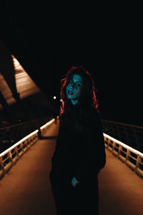 Young Woman Standing on Bridge at Night