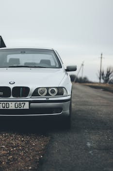 Close-up view of a classic BMW on a rural road, emphasizing its design and presence.