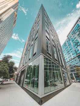 Dynamic low angle capture of a downtown skyscraper with glass facades on a sunny day.