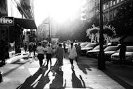 阳光明媚的城市街道上，人们走在黑白照片里，影子很长