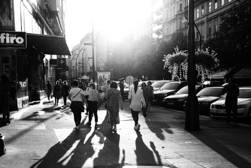 Free Black and white photo of people walking on a sunlit city street with long shadows. Stock Photo