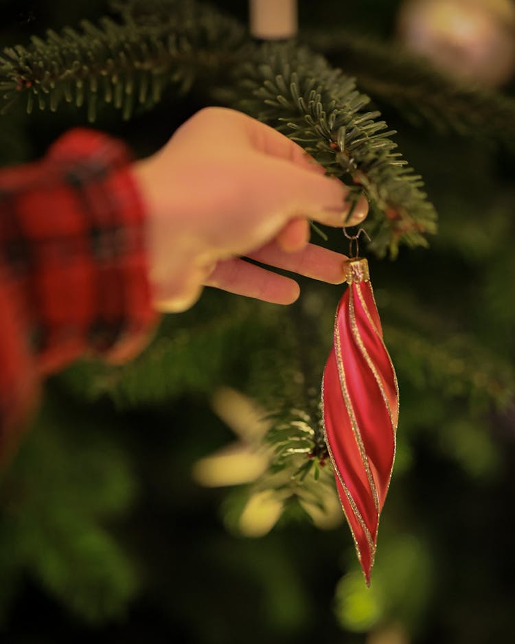 Child Hanging A Bauble On The Christmas Tree