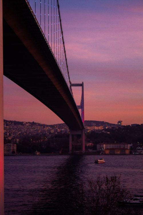 Free Scenic view of the Bosphorus Bridge in Istanbul at twilight with city lights reflecting on the water. Stock Photo