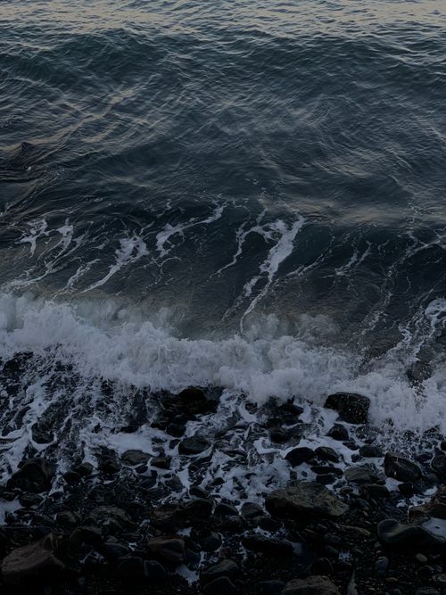 Free Peaceful ocean waves gently crash onto a rocky shoreline, creating a soothing coastal scenery. Stock Photo