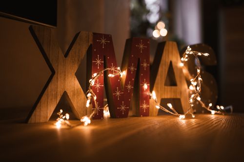 Free Xmas sign adorned with glowing fairy lights, creating a warm festive atmosphere indoors. Stock Photo