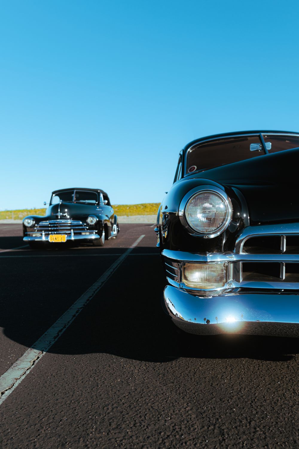 Two vintage cars parked on a sunny day