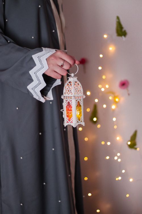 Free A woman in traditional attire holds a decorative lantern with sparkling background lights, creating a festive atmosphere. Stock Photo