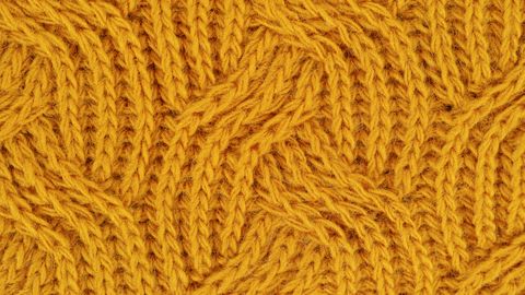 Detailed close-up of a yellow knitted wool pattern, ideal for textile design.