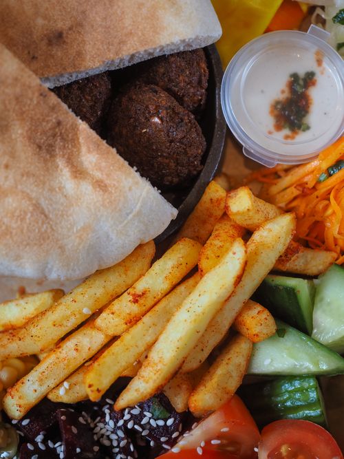 Free Mouthwatering close-up of a falafel platter with fries and fresh vegetables. Stock Photo