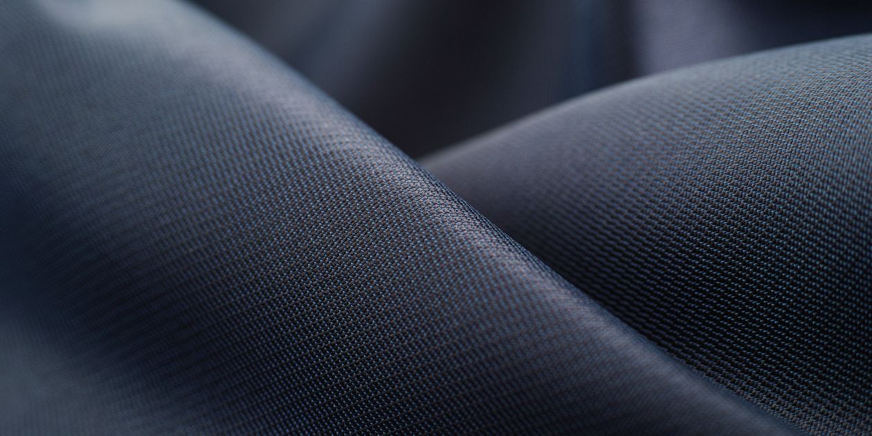 Vải lụa polyester màu navy cho thấy độ rủ và bề mặt mờ nhẹ