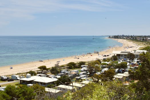 Scenic aerial view of Glenelg Beach, Adelaide featuring coastline, clear blue sea, and vacation vibe.