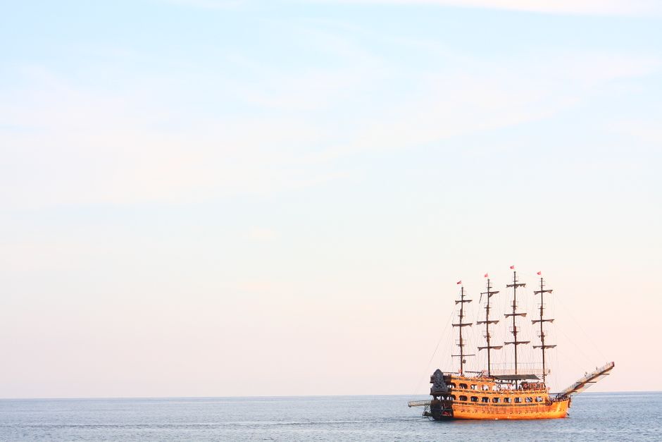 A majestic pirate ship sails the calm waters at sunset in Alanya, Turkey.