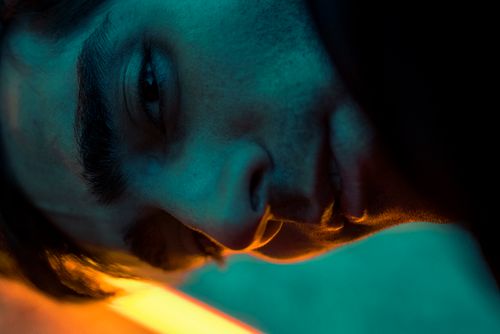 Free Close-up portrait of a man with dramatic blue and orange lighting, emphasizing shadows and intrigue. Stock Photo