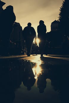 日落时分，街景优美，剪影人物行走其中，水中的倒影营造出忧郁的氛围