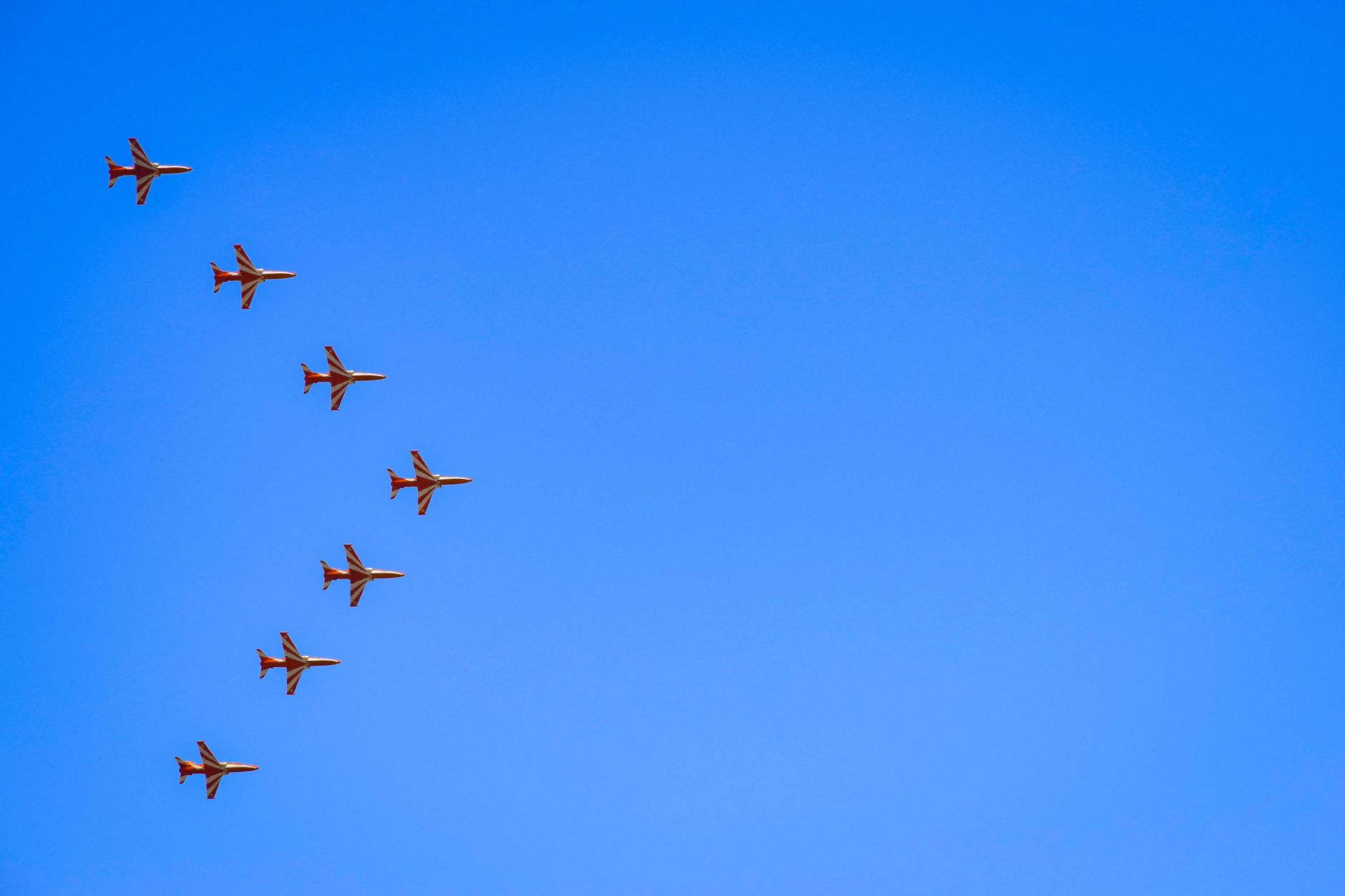 Aerial view of military jets flying in formation against a clear blue sky.
