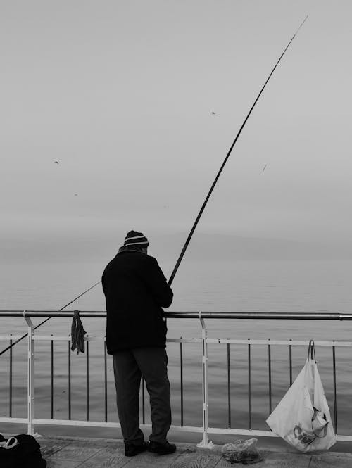 Grayscale Photo of Man Fishing