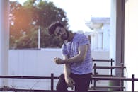 一名年轻人摆出休闲的姿势，在户外散发着轻松无忧无虑的氛围