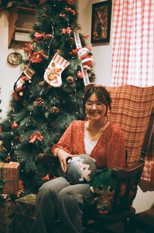 Smiling Woman Sitting next to Christmas Tree