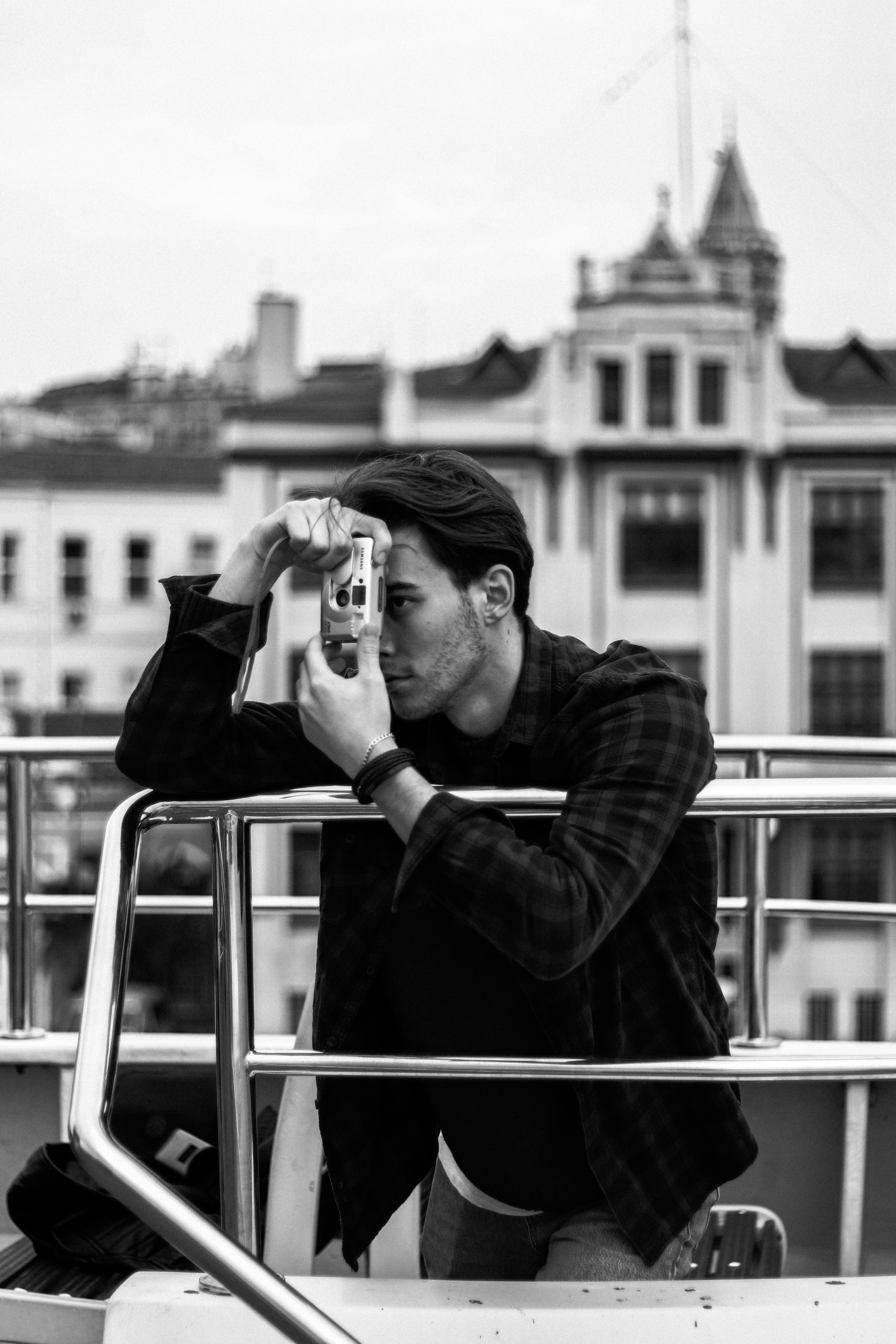 A man with a vintage camera taking a photo in an urban setting.