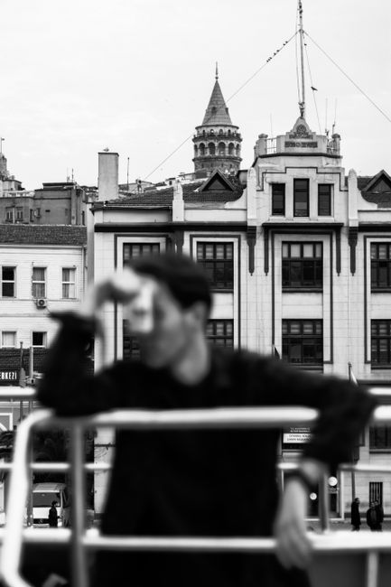 Black and white photo featuring a blurred man and Galata Tower in Istanbul.