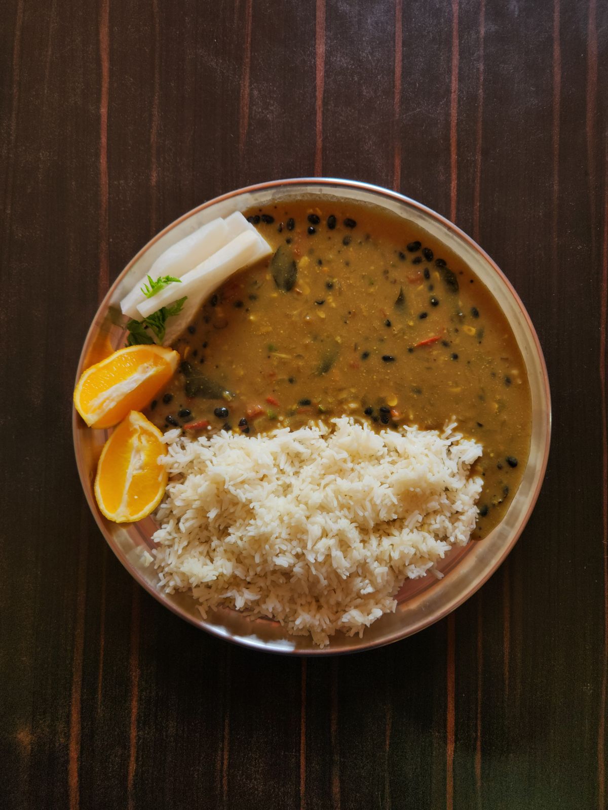 Traditional Nepali Dal Bhat meal on wooden table at mountain tea house with Himalayan view