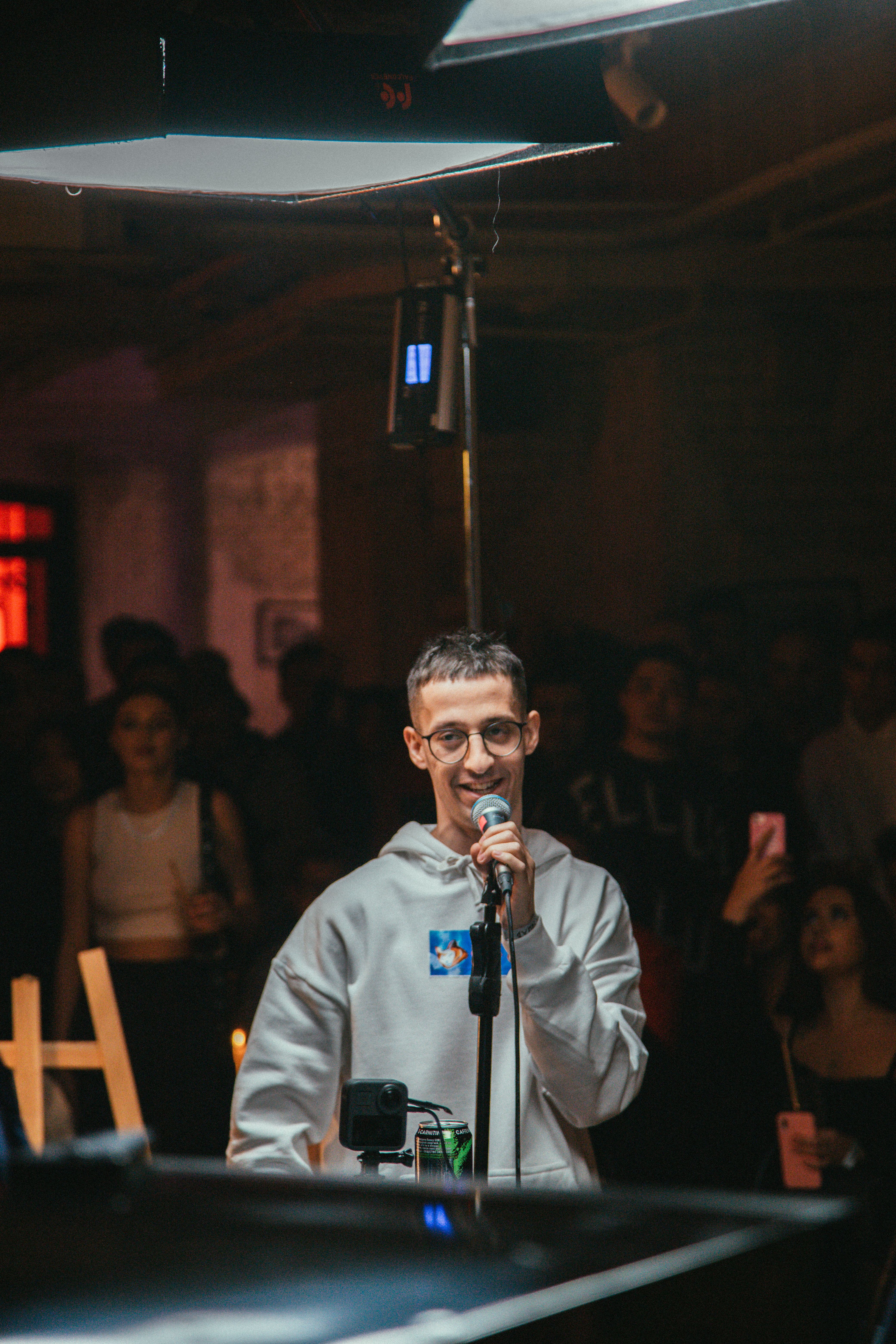 Young male singer performing live in a lively nightclub setting, engaging crowd.