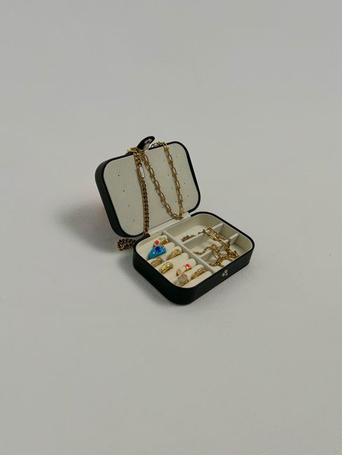 Open jewelry box showcasing a collection of elegant gold necklaces and rings.