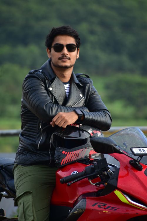 Free Confident motorcyclist posing with sunglasses on a red bike outdoors. Stock Photo