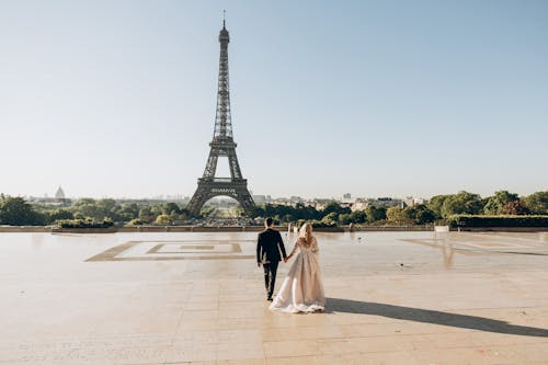 Free Woman and Man Walking in Park in Front of Eiffel Tower Stock Photo