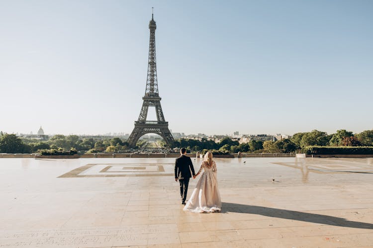 Woman And Man Walking In Park In Front Of Eiffel Tower