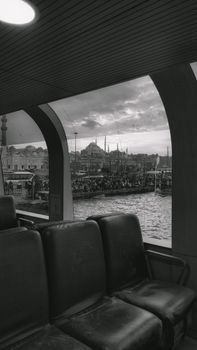 Black and white view of Istanbul cityscape from a ferry window, showcasing iconic mosque skyline.