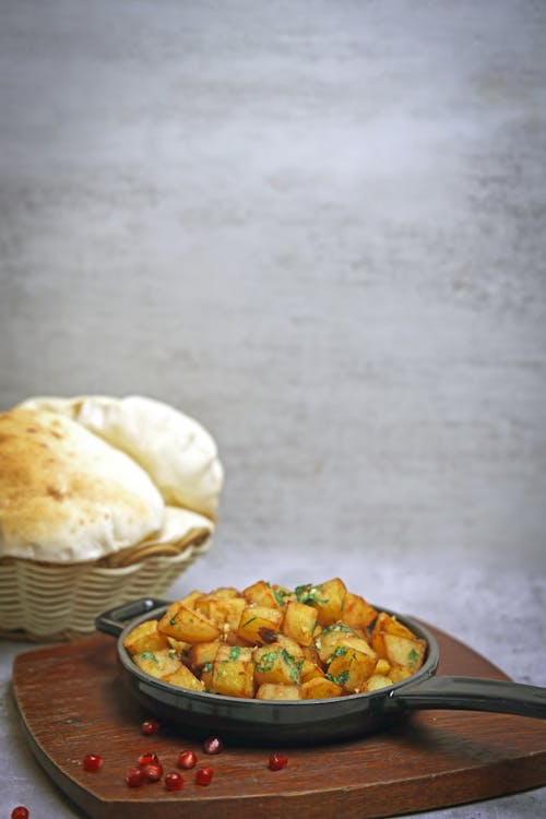 A pan with potatoes and bread on a cutting board